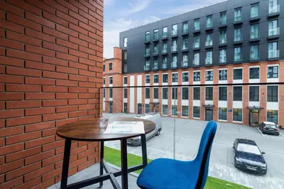 a table and chairs on a balcony with a building at Fabryczna City Kraków by Renters by Noclegi Renters in Kraków