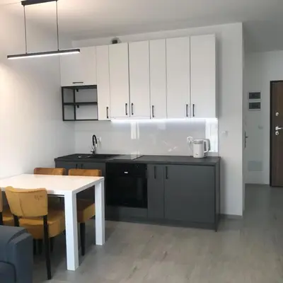 a kitchen with white cabinets and a table and chairs at Apartament BARCELONA in Kraków