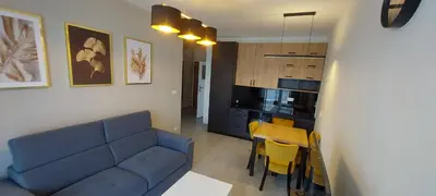 a living room with a blue couch and a kitchen at Apartament BARCELONA in Kraków