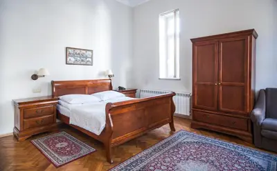 a bedroom with a bed and a cabinet and a chair at Aparthotel Basztowa in Kraków
