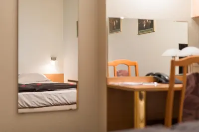 a mirror reflecting a bedroom with a bed and a desk at Jordan Pokoje Gościnne in Kraków
