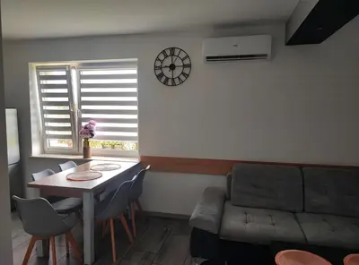 a living room with a table and a couch and a clock at Apartamenty NOVA in Zator