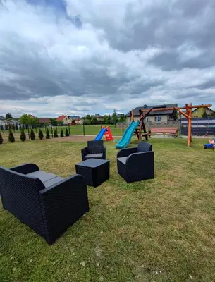 a group of chairs in a park with a playground at Apartamenty NOVA in Zator