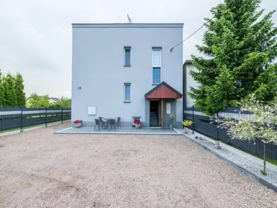 a white house with a fence and a tree at Apartamenty NOVA in Zator
