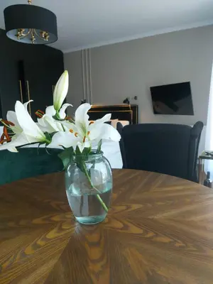 a vase filled with white flowers sitting on a table at Doris Day Apartment in Kraków