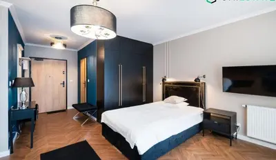a bedroom with a bed and a desk and a television at Doris Day Apartment in Kraków