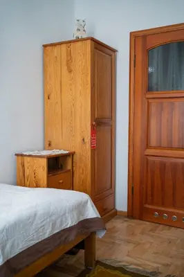 a bedroom with a bed and a wooden cabinet at Kolory Guest House in Kraków