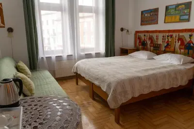 a bedroom with a bed and a couch and two windows at Kolory Guest House in Kraków