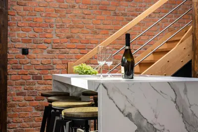 a bottle of wine sitting on a table with wine glasses at Riverside Premium Class Apartment - by Upstairs in Kraków