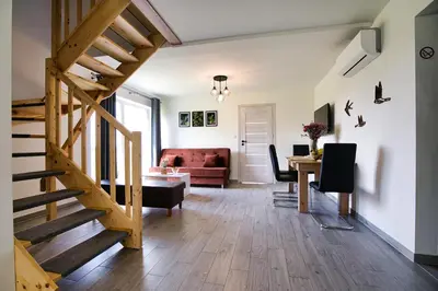 a living room with a wooden staircase and a table at HOUSE OF ENERGY - Zator Przeciszów in Przeciszów