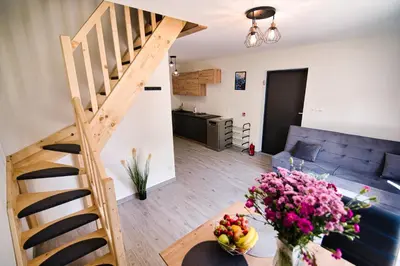 a living room with a staircase and a table with flowers at HOUSE OF ENERGY - Zator Przeciszów in Przeciszów