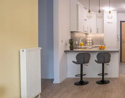a kitchen with two bar stools and a counter at Przytulny apartament z ogródkiem in Kraków