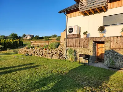 a house with a grassy yard next to a building at Apartament u Ewki in Rdzawka