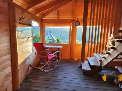 a rocking chair sitting on the porch of a cabin at Apartament u Ewki in Rdzawka