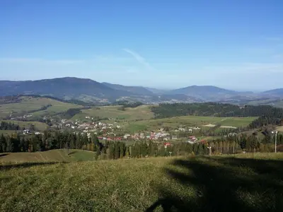 a green hillside with a town in the distance at Apartament u Ewki in Rdzawka