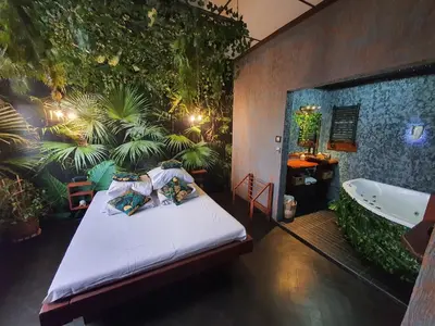 a bedroom with a bed and a bath tub and plants at Tropicana Jacuzzi Apartment in Kraków