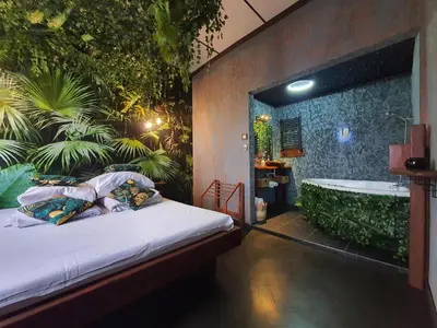 a bedroom with a bath tub and a bed with pillows at Tropicana Jacuzzi Apartment in Kraków