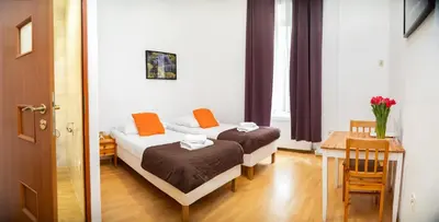 two beds in a small room with a table and a table sidx sidx at Station Aparthotel in Kraków