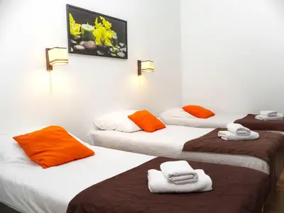 three beds in a room with orange and white towels at Station Aparthotel in Kraków