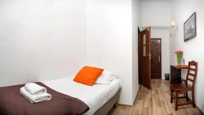 a bedroom with a bed with an orange pillow on it at Station Aparthotel in Kraków