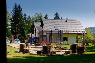 a playground in front of a house with a building at Domki Pod Lasem MM in Rabka