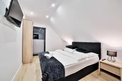 a bedroom with a large bed and a flat screen tv at Domki Pod Lasem MM in Rabka