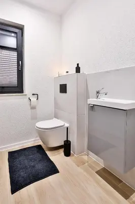 a white bathroom with a toilet and a sink at Domki Pod Lasem MM in Rabka