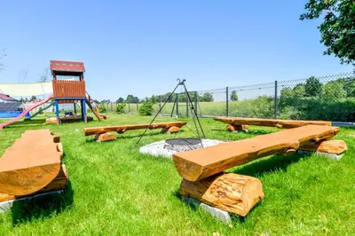 a group of wooden benches in a field with a playground at KempingZator in Zator