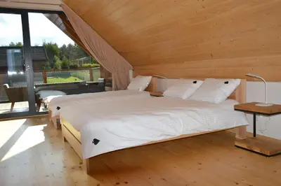 a bedroom with two beds and a large window at Tarnawa Gold, Sauna, Jacuzzi, Grota solna, in Tarnawa Dolna
