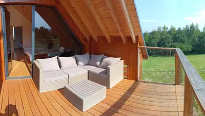 a porch with a couch on a wooden deck at Tarnawa Gold, Sauna, Jacuzzi, Grota solna, in Tarnawa Dolna