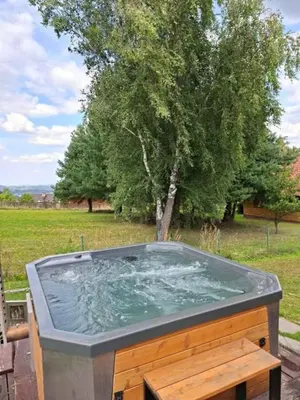 a jacuzzi tub in a yard with a tree at Tarnawa Gold, Sauna, Jacuzzi, Grota solna, in Tarnawa Dolna