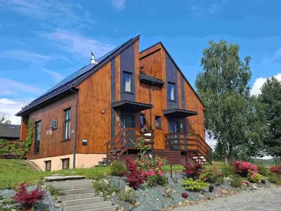 a large wooden house with stairs and flowers at Tarnawa Gold, Sauna, Jacuzzi, Grota solna, in Tarnawa Dolna