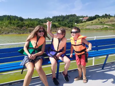 three girls and a woman sitting on a bench on a boat at Tarnawa Gold, Sauna, Jacuzzi, Grota solna, in Tarnawa Dolna