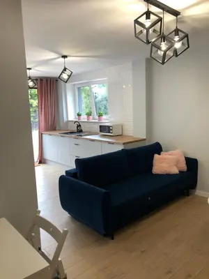 a living room with a blue couch and a kitchen at Apartament 15G in Skawina
