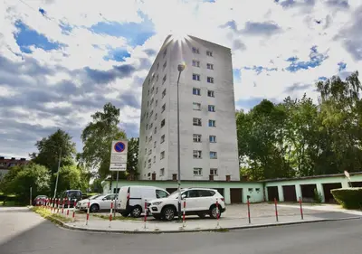 a tall white building with cars parked in a parking lot at Czarnowiejska Mini Studio in Kraków