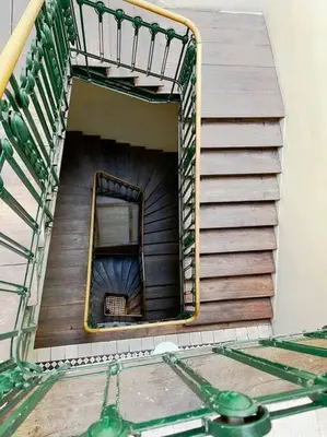 a spiral stairwell in a building with a ladder at Pod Słońcem - Rynek Główny in Kraków