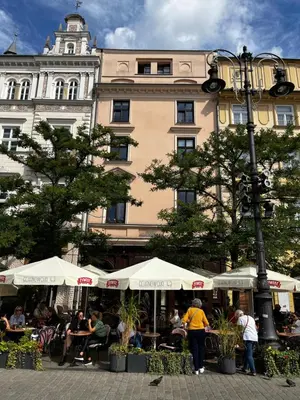 people sitting at tables in front of a building at Pod Słońcem - Rynek Główny in Kraków