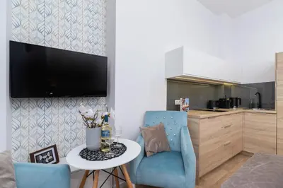 a living room with a table and a blue chair at Beautiful Apartments Kraków Dietla by Noclegi Renters in Kraków