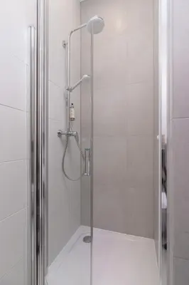 a shower with a glass door and a shower head at Beautiful Apartments Kraków Dietla by Noclegi Renters in Kraków