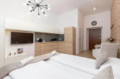 a white bedroom with a large bed and a kitchen at Beautiful Apartments Kraków Dietla by Noclegi Renters in Kraków