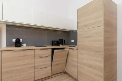 a kitchen with wooden cabinets and a counter top at Beautiful Apartments Kraków Dietla by Noclegi Renters in Kraków