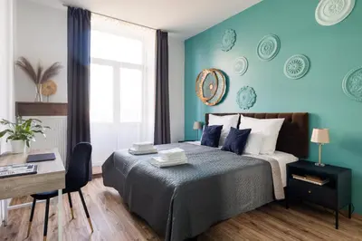 a bedroom with blue walls and a bed with a desk at Luxe Living Castle View in Kraków