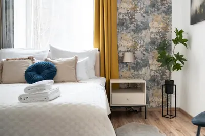 a bedroom with a white bed with a yellow curtain at Luxe Living Castle View in Kraków