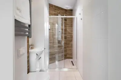a white bathroom with a shower and a toilet at Luxe Living Castle View in Kraków