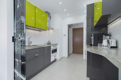a kitchen with gray and green cabinets and a counter top at Kraków Błonia Apartment with Balcony by Noclegi Renters in Kraków