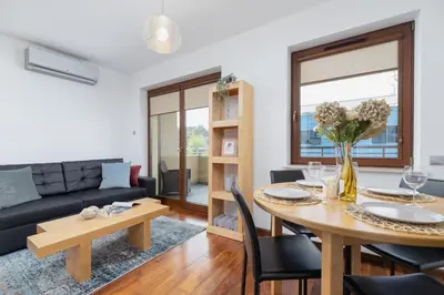 a living room with a table and a couch at Kraków Błonia Apartment with Balcony by Noclegi Renters in Kraków