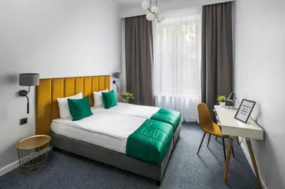 a bedroom with a bed with green pillows and a desk at Modern & cozy flat - near to Wawel Castle in Kraków