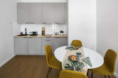 a white kitchen with a table and chairs at Modern & cozy flat - near to Wawel Castle in Kraków