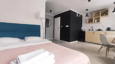 a bedroom with a large bed and a kitchen at Na Szaniec 17 by Homeprime in Kraków
