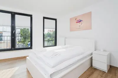 a white room with a large bed with windows at Mieszczańska 10 by Homeprime in Kraków